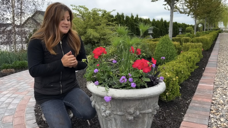 Laura from Garden Answer on Youtube kneeling beside a flower pot