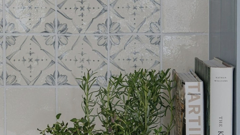 A close-up of kitchen tiles with blue floral patterned tiles bordered by plain cream tiles