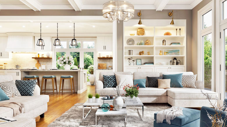Open plan interior with grey and blue couches, a built in bookcase and a kitchen island.