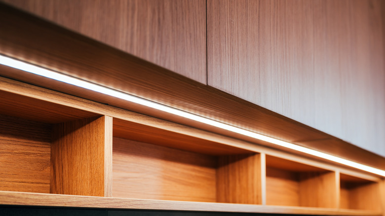 A bright strip of lights is mounted under wood veneer cabinets