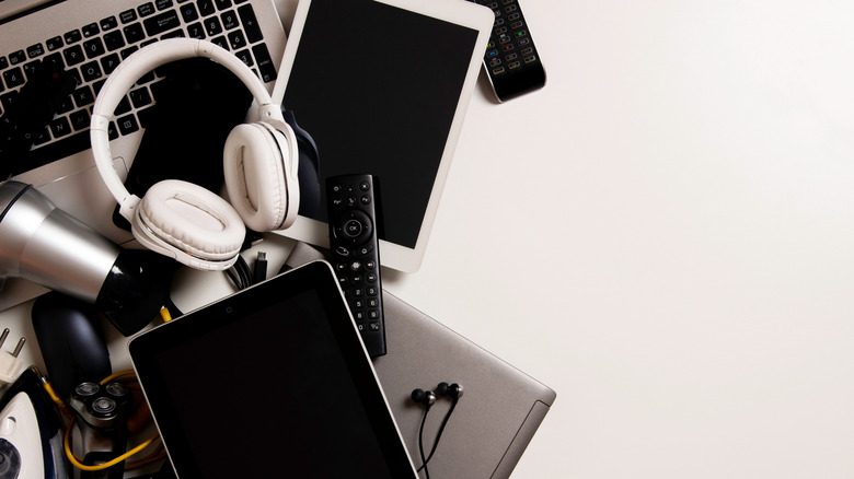 Pile of older electronics like laptop, tablets, headphones