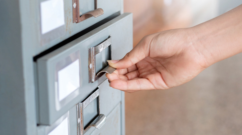 Hand opening a metal filing cabinet