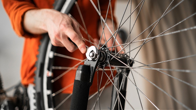 Close-up of a person using a wrench to loosen a bicycle wheel
