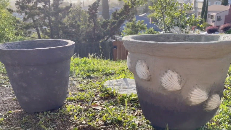 Two large empty planters made of papercrete sit on the lawn in a garden.