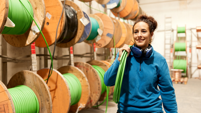 A woman walking past a wall of wooden spools holding cables