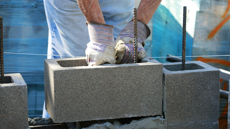 man stacking cinder blocks on construction site
