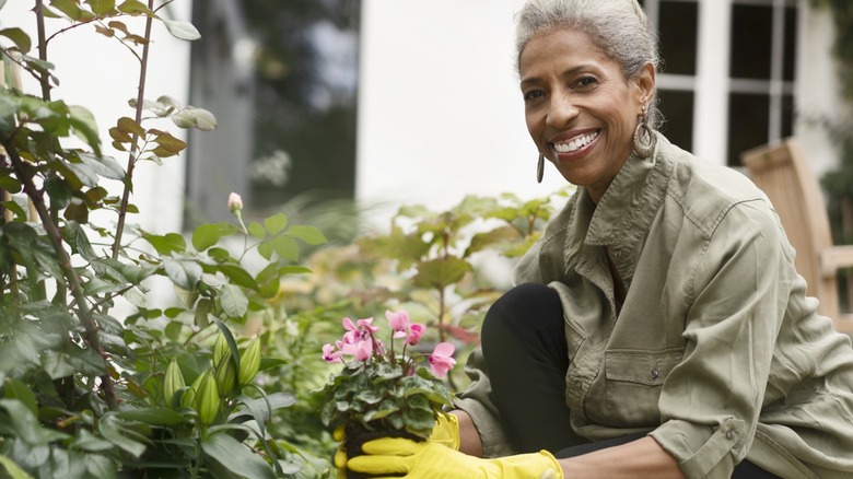 Happy woman holding plant in garden