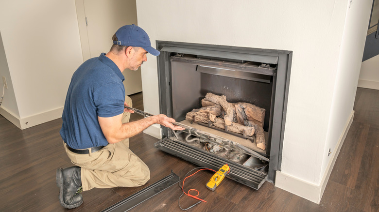 A service technician repairs a gas fireplace
