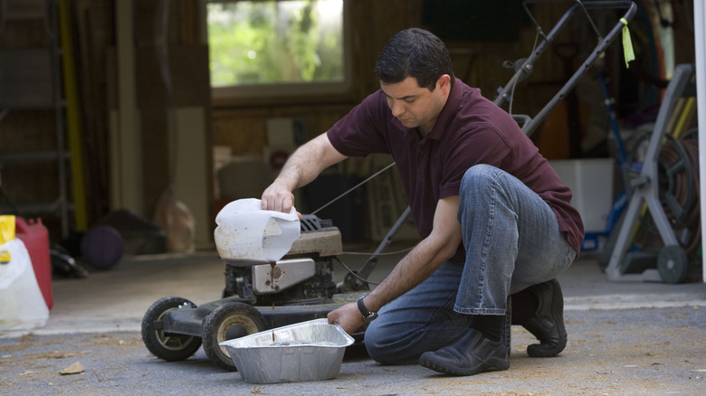 A man changing the oil in a lawn mower