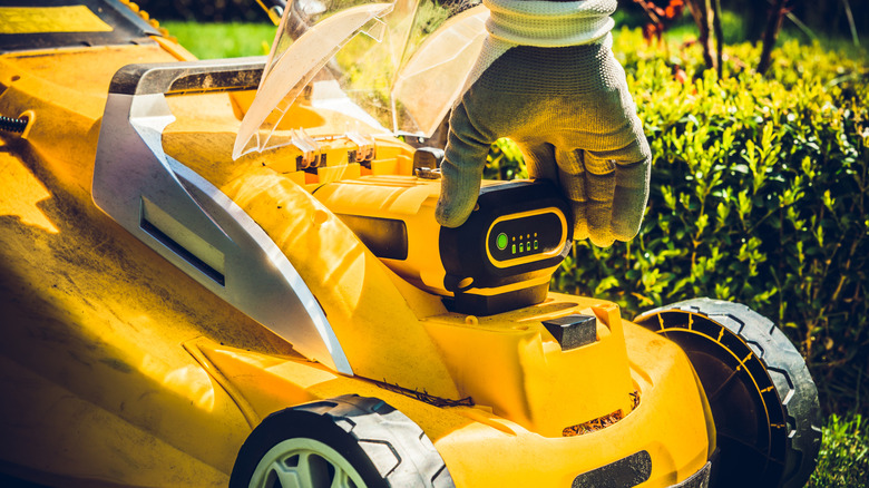 Person inserting the battery in a lawn mower