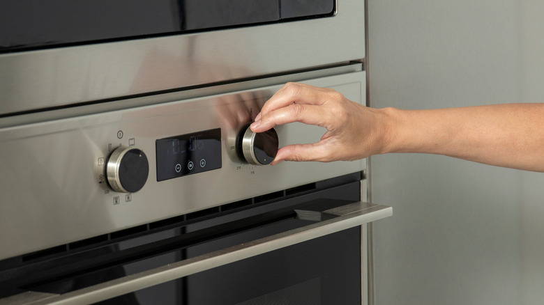 A person adjusts the temperature on a modern oven