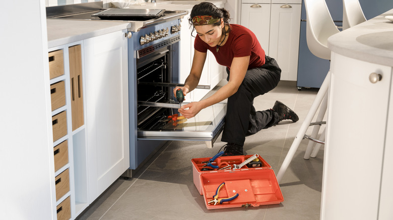A repair technician works on fixing an oven