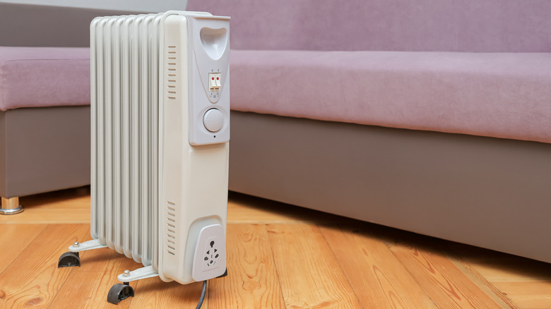 An oil heater standing on the floor near a sofa