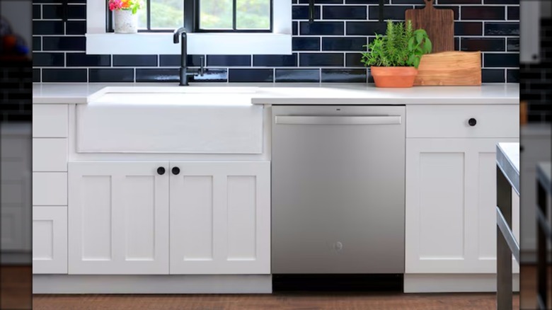 A built-in stainless steel GE dishwasher is surrounded by white kitchen cabinets