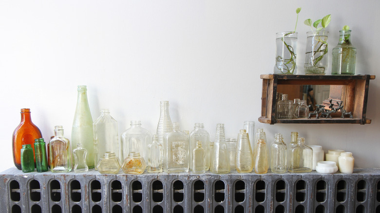 Antique glass bottles displayed on a sideboard against a white wall.