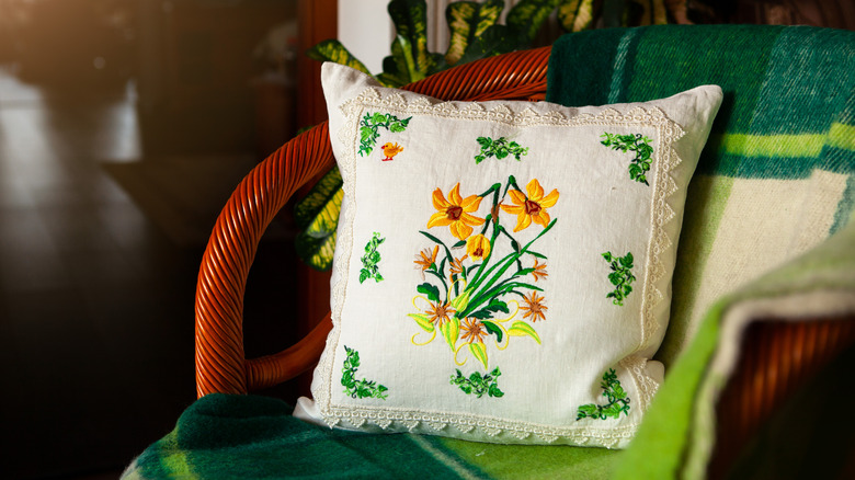 An embroidered pillow with daffodils and flowers sewn onto it.
