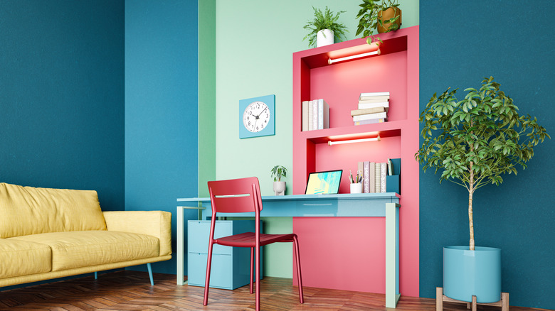 A colorful living room with painted walls, pink bookshelves, and yellow furniture.