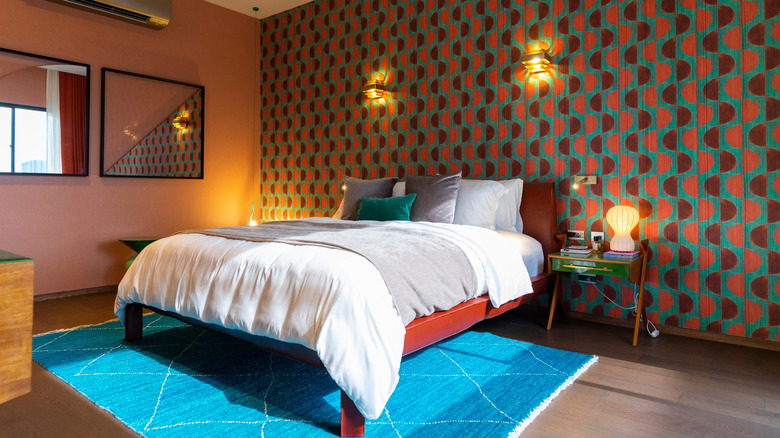 A bedroom with a retro wallpaper focal wall.