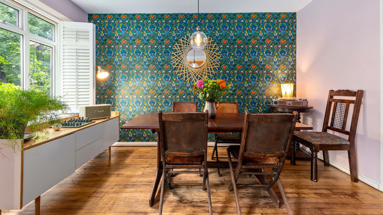 A dining room with bold wallpaper and retro furniture and light fixtures.