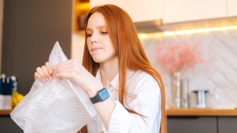 A stressed woman popping bubble wrap 