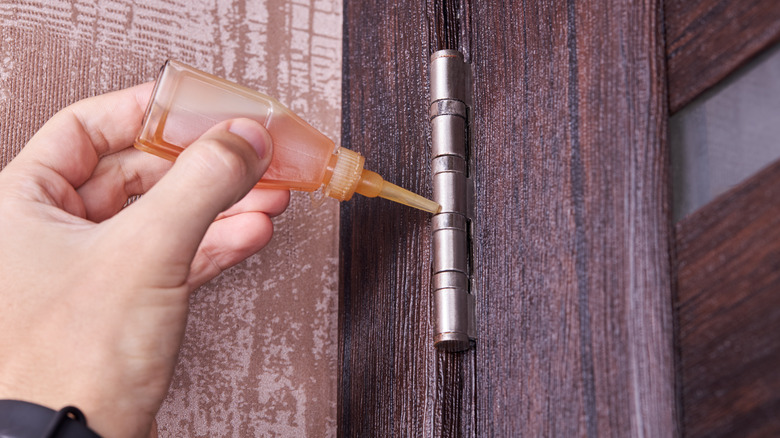 person oiling door hinges