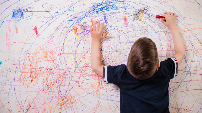 child drawing on wall crayon