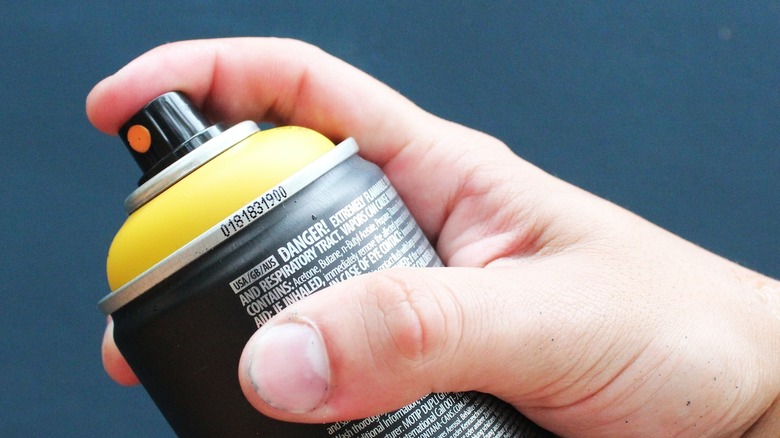 person holding spray paint can