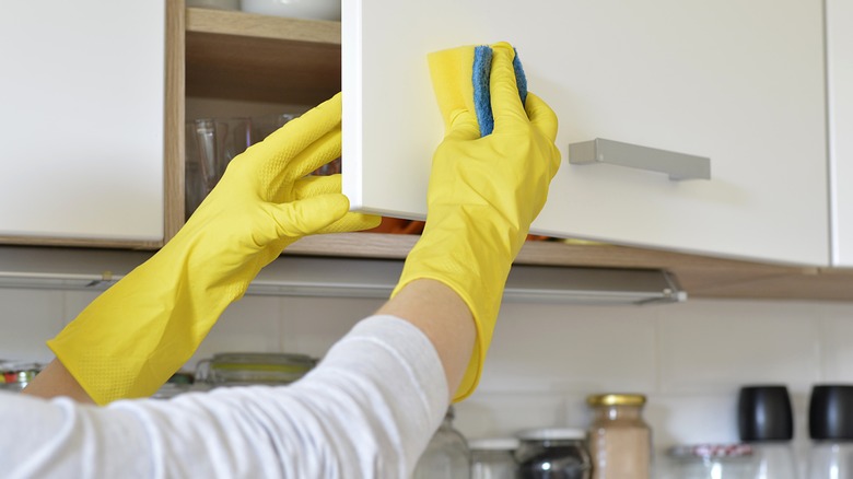 person cleaning kitchen cabinets