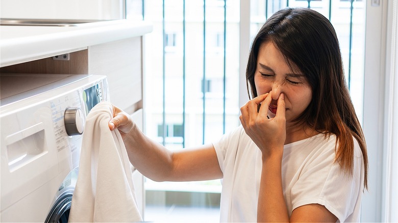 Woman holding nose smelly laundry
