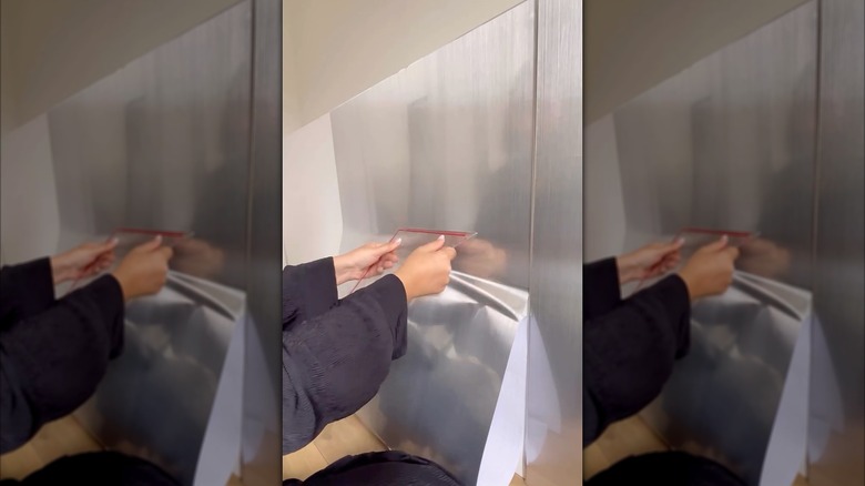 Smoothing chrome contact paper onto an IKEA cabinet