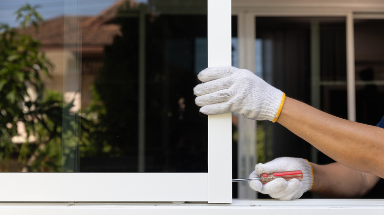 pair of gloved hands adjusting window