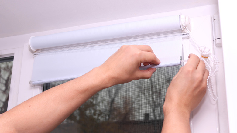 Close up of man hands installing roller blinds on the window