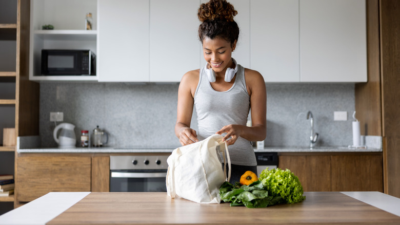 Woman unpacking a bag of produce in her kitchen