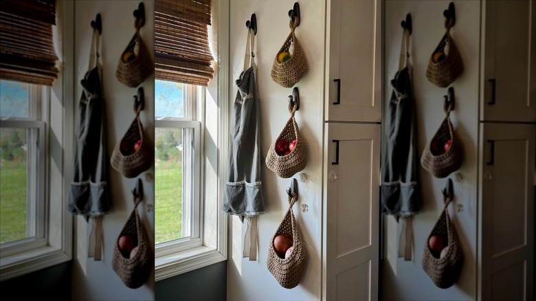Hanging baskets holding fruit in a kitchen aside an open window