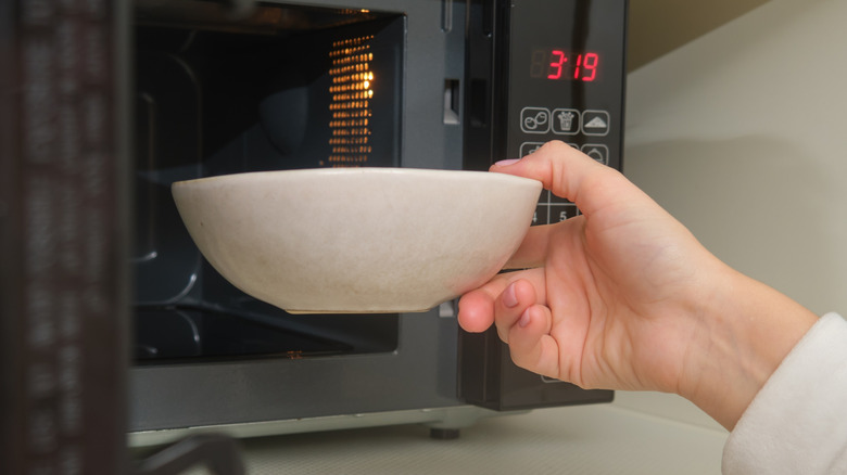 Woman's hand removing bowl from microwave