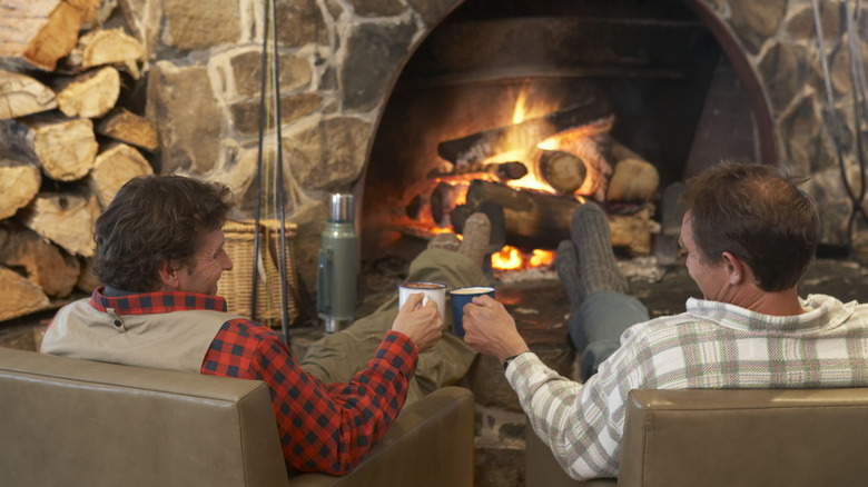 Two men sitting around a fireplace