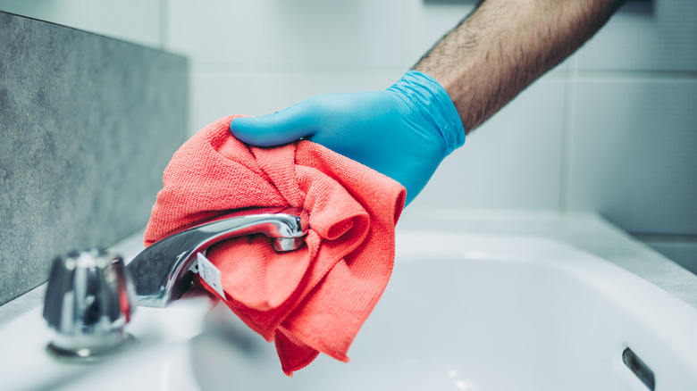 man cleaning bathroom sink hardware