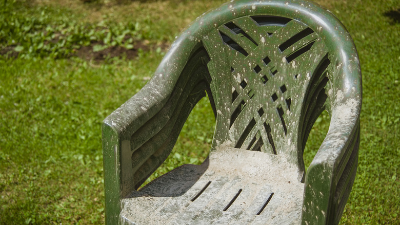 Dirt covered green plastic chair in a yard