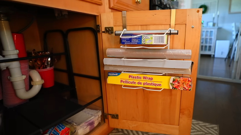 Towel bar and dish rack used to hang plastic wrap, etc on cabinet door of kitchen