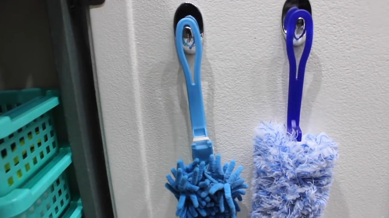 Scrub brushes hanging on silver hooks inside a bathroom cabinet