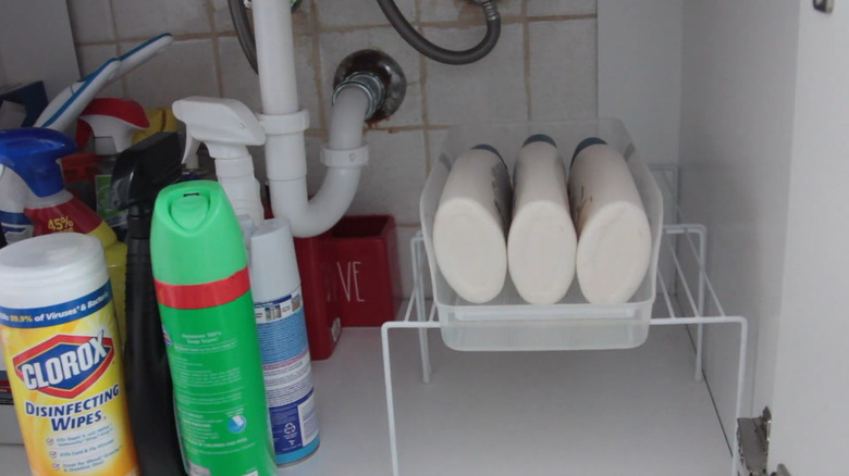 Body wash nestled in a fridge can caddy on a wire shelf in bathroom sink cabinet