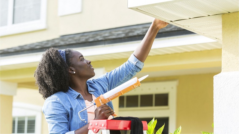 Person using caulking gun outside