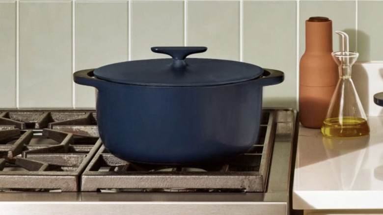 A Caraway brand Dutch oven on a stovetop.