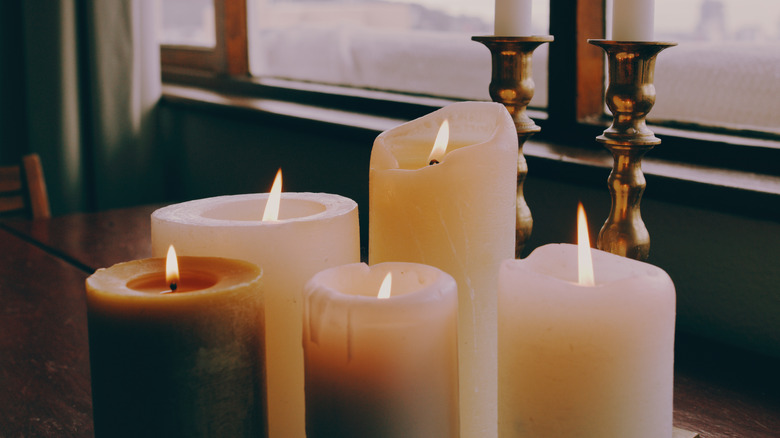 Candles sitting on table with candle stick holders in background