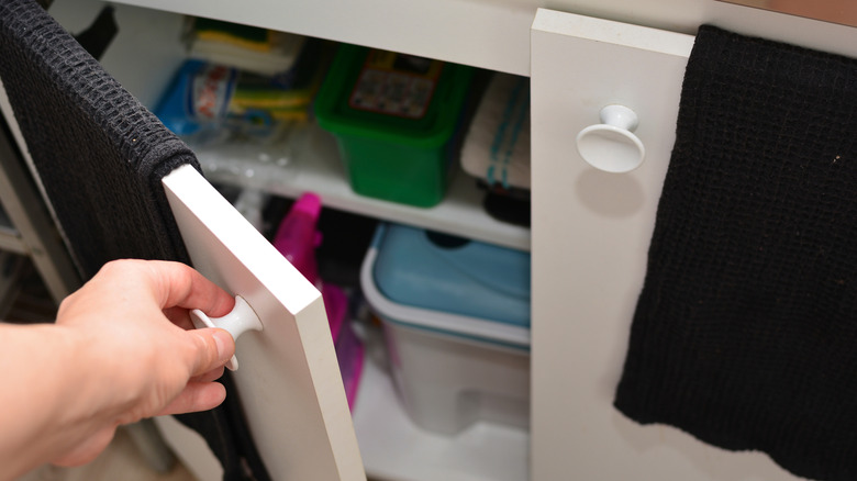 person opening under sink cabinet
