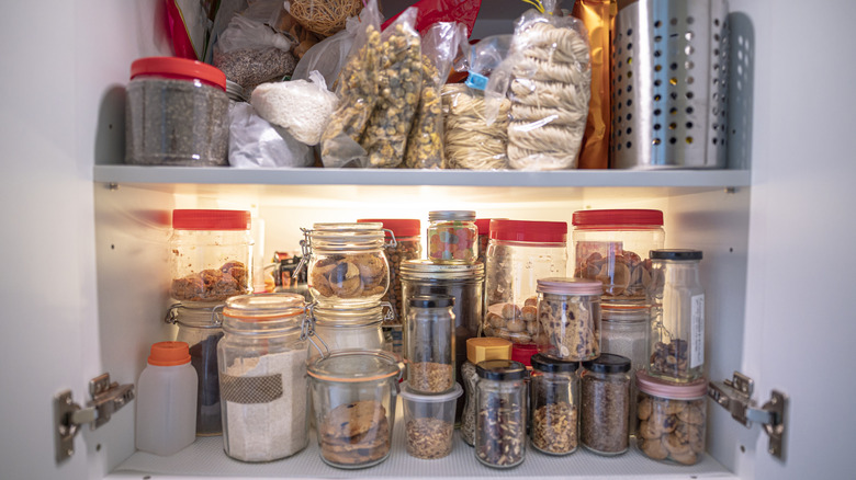 Pantry cupboard stuffed full of dry goods and containers of foods