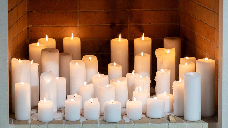 Collection of white candle pillars in fireplace