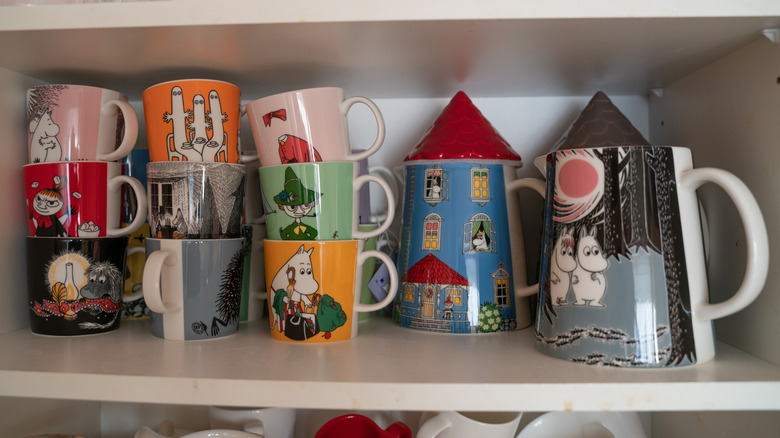 Moomin mugs stacked in a cupboard shelf