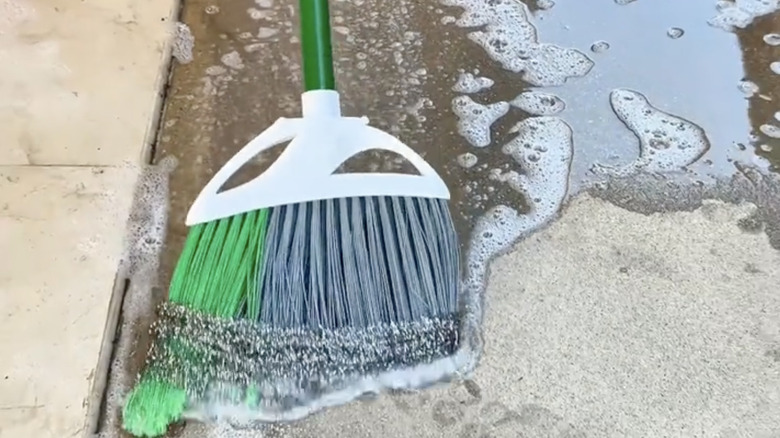 Steel wool wrapped around a broom's bristles, used as an extended scrubber for concrete driveway.