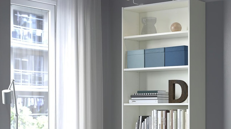 three blue IKEA DRÖNA storage boxes on a shelf beside a window